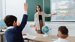 Eine junge Lehrerin steht in einem im Klassenzimmer und unterrichtet.