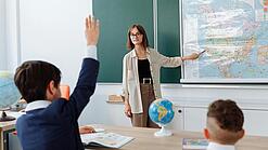Eine junge Lehrerin steht in einem im Klassenzimmer und unterrichtet.