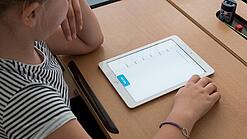 Eine Schülerin schaut auf ein Tablet.