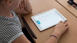 Eine Schülerin schaut auf ein Tablet.