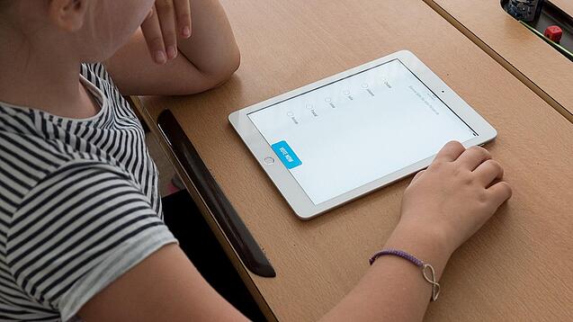 Eine Schülerin schaut auf ein Tablet.