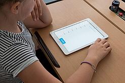 Eine Schülerin schaut auf ein Tablet.