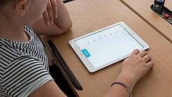 Eine Schülerin schaut auf ein Tablet.