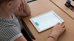 Eine Schülerin schaut auf ein Tablet.
