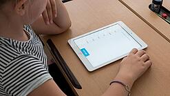 Eine Schülerin schaut auf ein Tablet.