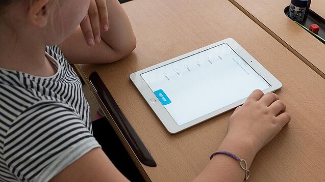 Eine Schülerin schaut auf ein Tablet.
