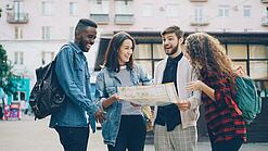 Eine Gruppe internationaler Studierender schaut auf einen Stadtplan und lacht.