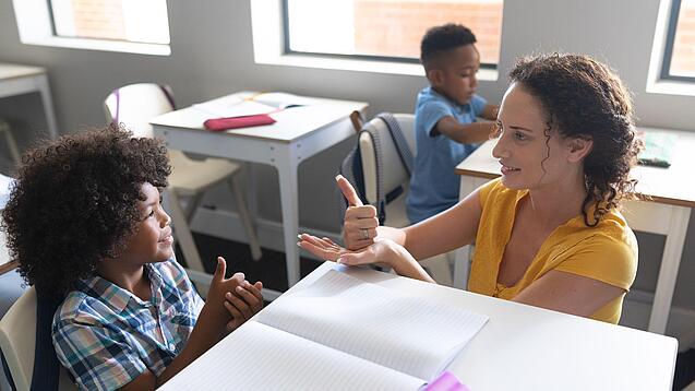 Junge Lehrerin übt mit einem Grundschulkind zählen.