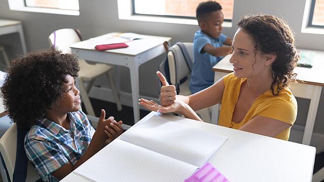 Junge Lehrerin übt mit einem Grundschulkind zählen.