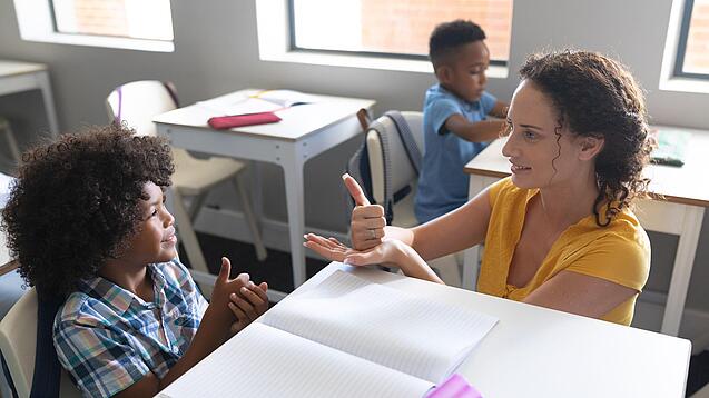 Junge Lehrerin übt mit einem Grundschulkind zählen.