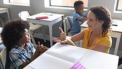 Junge Lehrerin übt mit einem Grundschulkind zählen.
