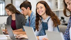 Mehrere Kinder arbeiten an aufgeklappten Laptops.