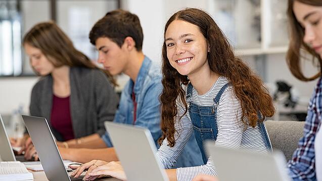 Mehrere Kinder arbeiten an aufgeklappten Laptops.
