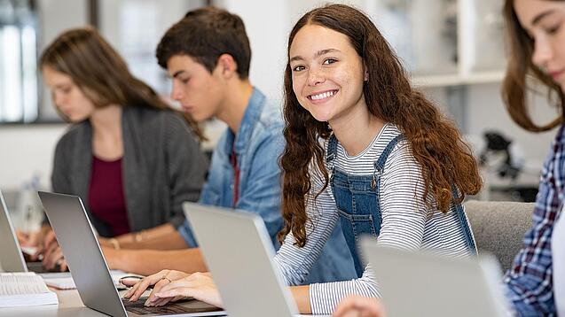 Mehrere Kinder arbeiten an aufgeklappten Laptops.