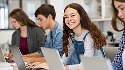 Mehrere Kinder arbeiten an aufgeklappten Laptops.