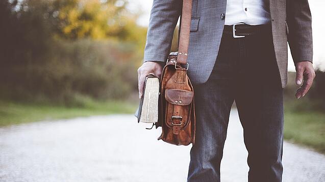 Lehrer auf dem Schulweg mit Umhängetasche.