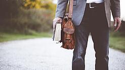 Lehrer auf dem Schulweg mit Umhängetasche.