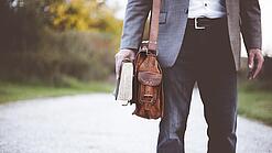 Lehrer auf dem Schulweg mit Umhängetasche.