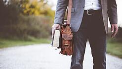 Lehrer auf dem Schulweg mit Umhängetasche.