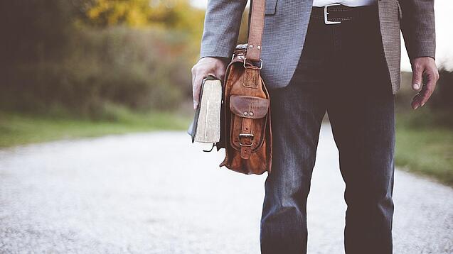 Lehrer auf dem Schulweg mit Umhängetasche.