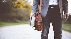 Lehrer auf dem Schulweg mit Umhängetasche.