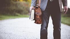 Lehrer auf dem Schulweg mit Umhängetasche.