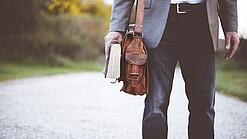 Lehrer auf dem Schulweg mit Umhängetasche.