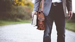 Lehrer auf dem Schulweg mit Umhängetasche.