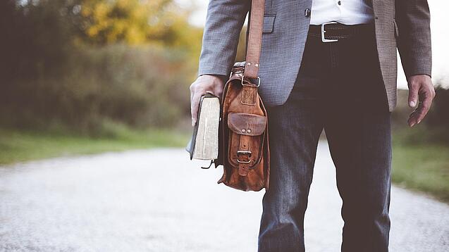 Lehrer auf dem Schulweg mit Umhängetasche.