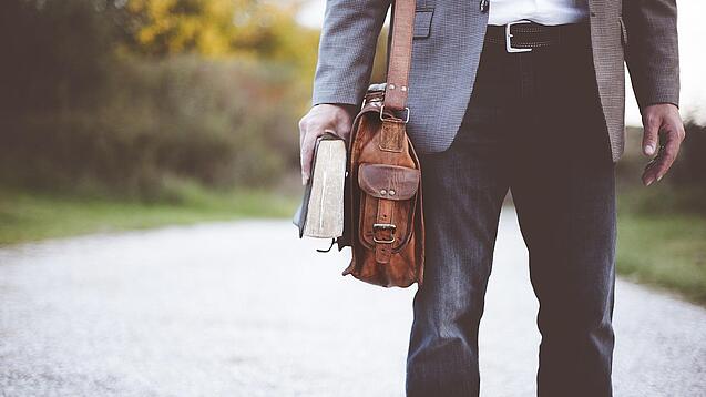 Lehrer auf dem Schulweg mit Umhängetasche.