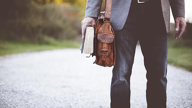 Lehrer auf dem Schulweg mit Umhängetasche.
