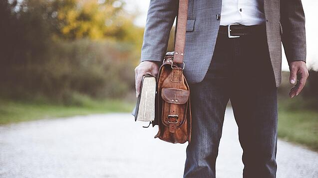 Lehrer auf dem Schulweg mit Umhängetasche.