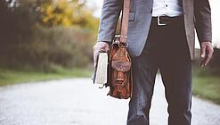 Lehrer auf dem Schulweg mit Umhängetasche.