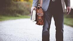 Lehrer auf dem Schulweg mit Umhängetasche.