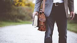 Lehrer auf dem Schulweg mit Umhängetasche.