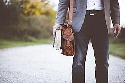 Lehrer auf dem Schulweg mit Umhängetasche.
