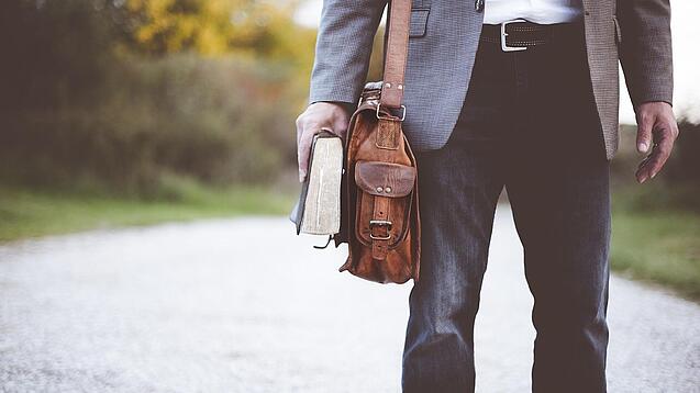 Lehrer auf dem Schulweg mit Umhängetasche.