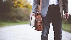 Lehrer auf dem Schulweg mit Umhängetasche.