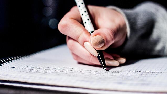 Die Hand einer Schülerin mit Stift und Block.