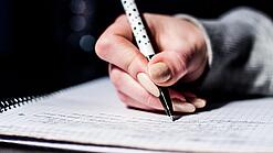 Die Hand einer Schülerin mit Stift und Block.