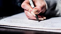 Die Hand einer Schülerin mit Stift und Block.