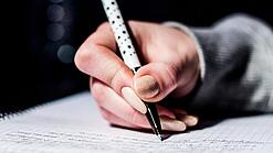 Die Hand einer Schülerin mit Stift und Block.