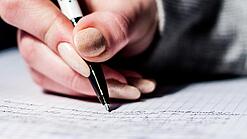 Die Hand einer Schülerin mit Stift und Block.