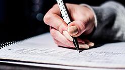 Die Hand einer Schülerin mit Stift und Block.