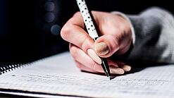 Die Hand einer Schülerin mit Stift und Block.