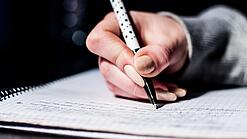 Die Hand einer Schülerin mit Stift und Block.