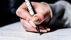 Die Hand einer Schülerin mit Stift und Block.