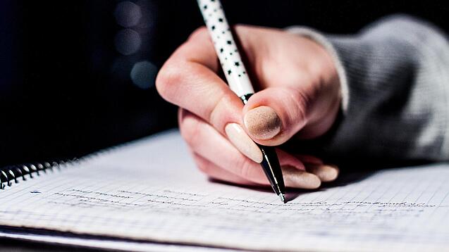 Die Hand einer Schülerin mit Stift und Block.