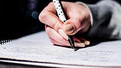 Die Hand einer Schülerin mit Stift und Block.
