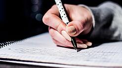 Die Hand einer Schülerin mit Stift und Block.